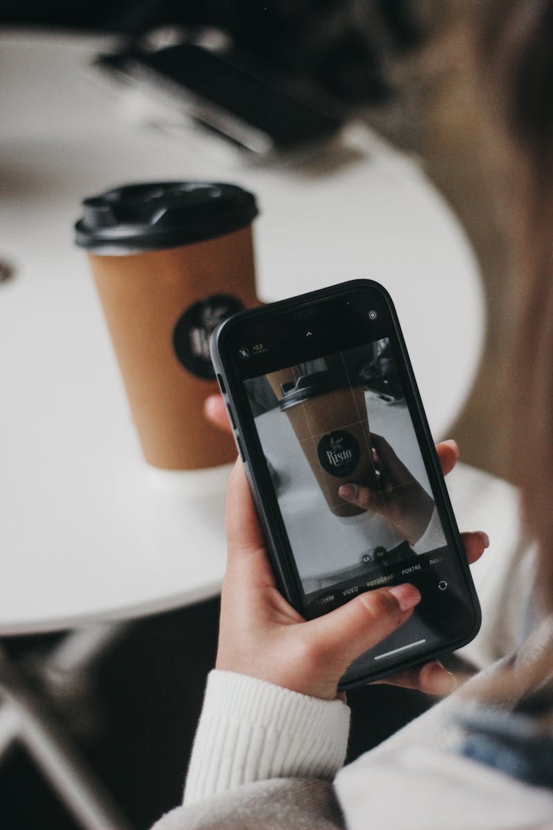 Woman captures a coffee cup image using a smartphone, indoors.